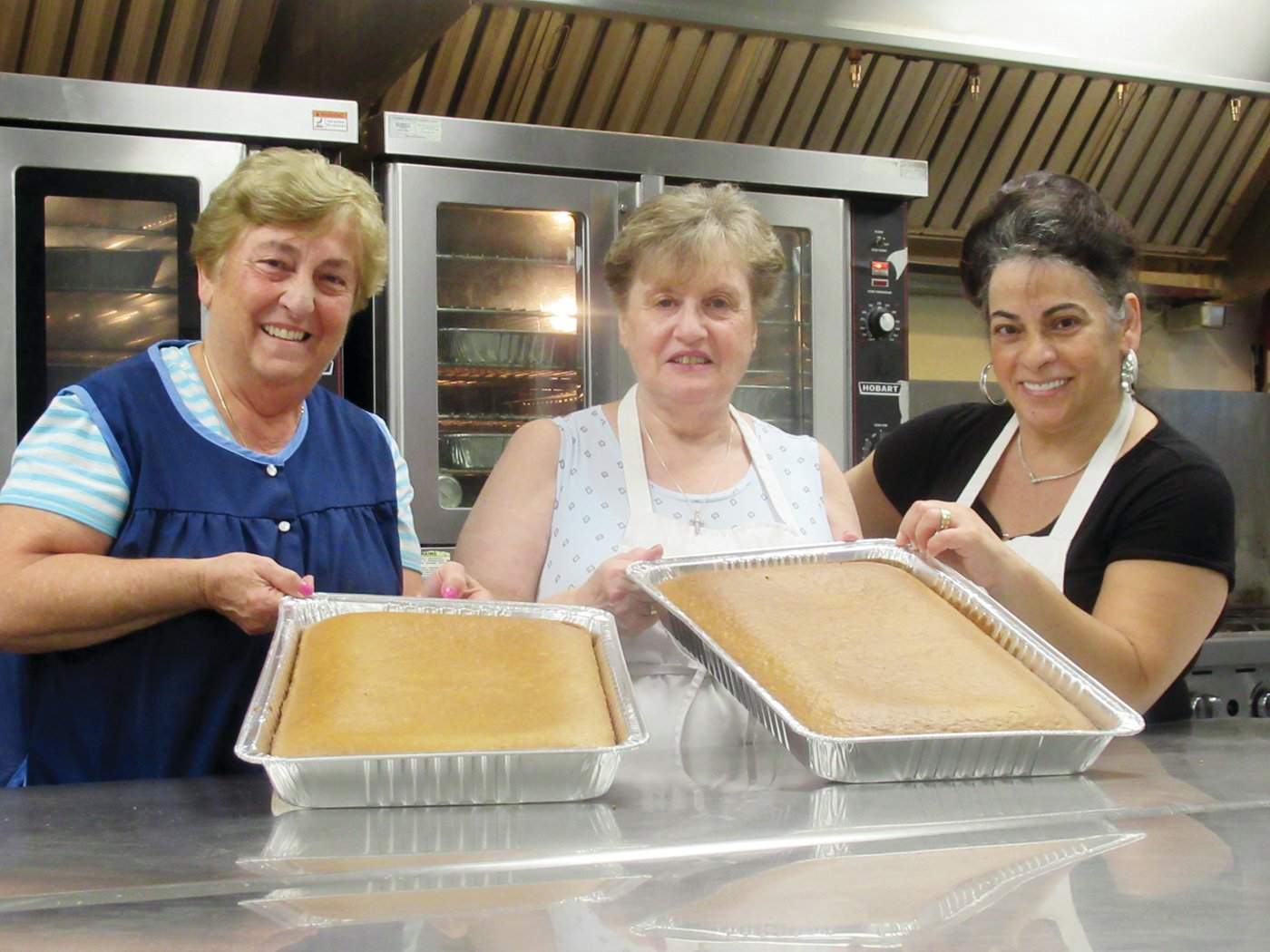 Koula Rougas, Roula Proyous and Hoda Daiaa hold two trays of specially made honey nut cake -- Karydopita – one of the many Greek pastries that will be featured this weekend in Cranston.